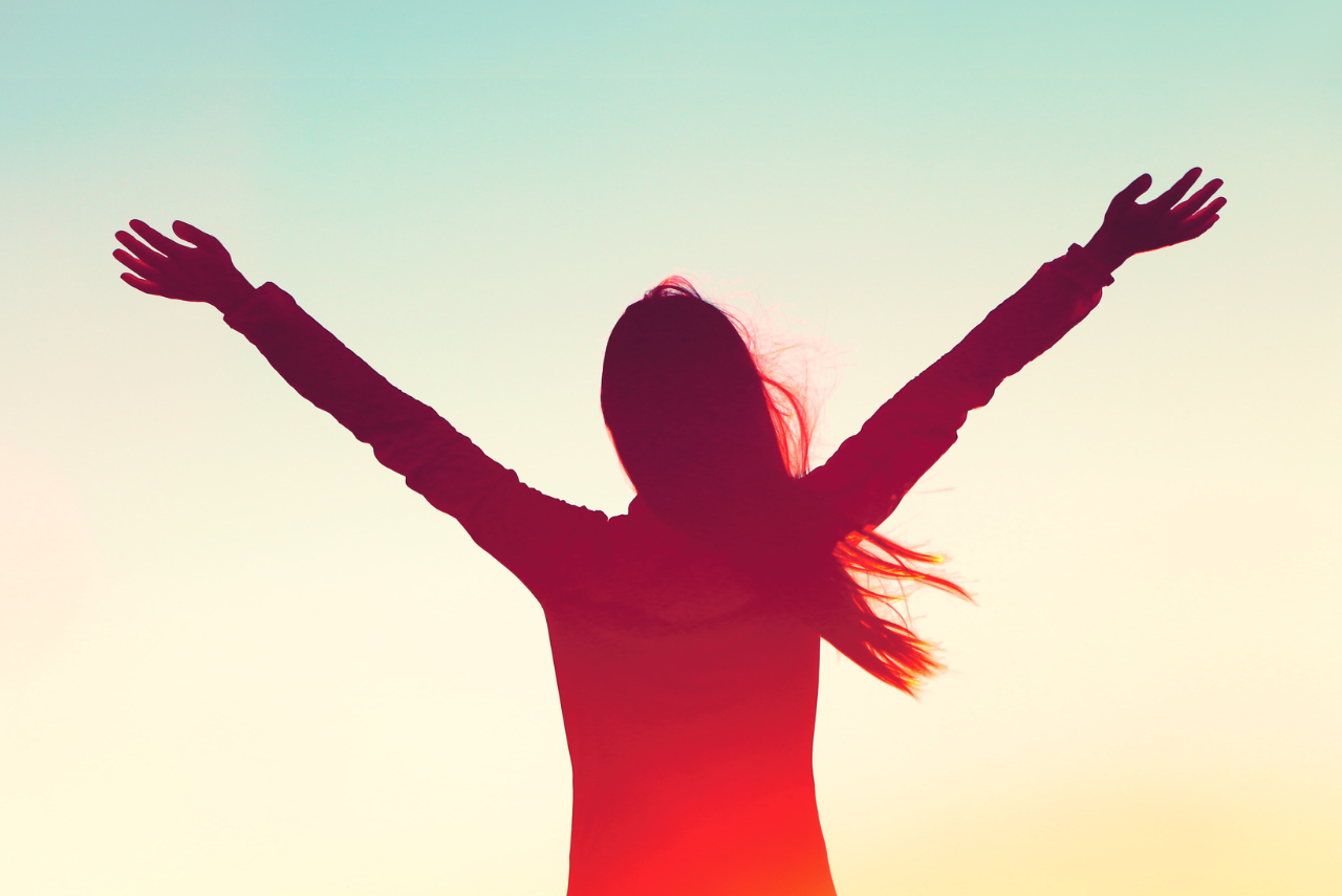 Silhouette of woman with arms up to the sky rejoicing